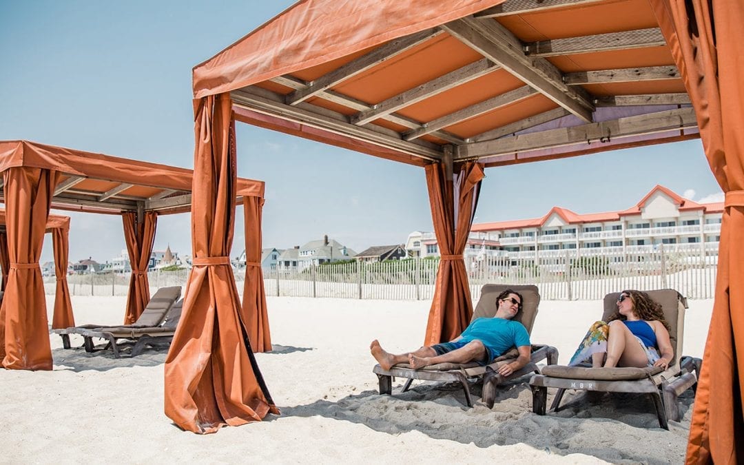 Couple relaxing in beach cabana in front of Montreal Beach Resort.